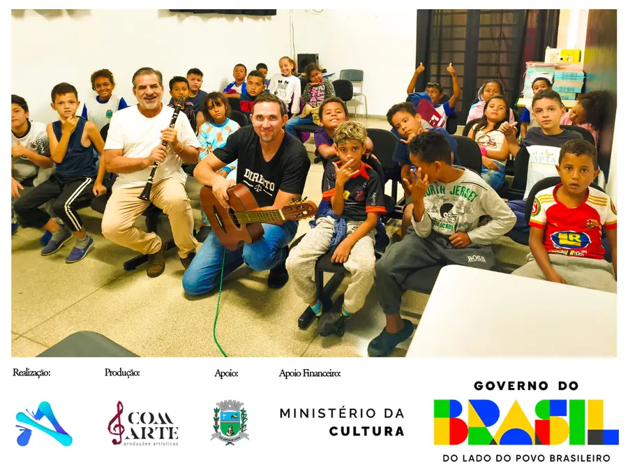 Crianças e professores do projeto de música, com clarinete e violão, em sala de aula