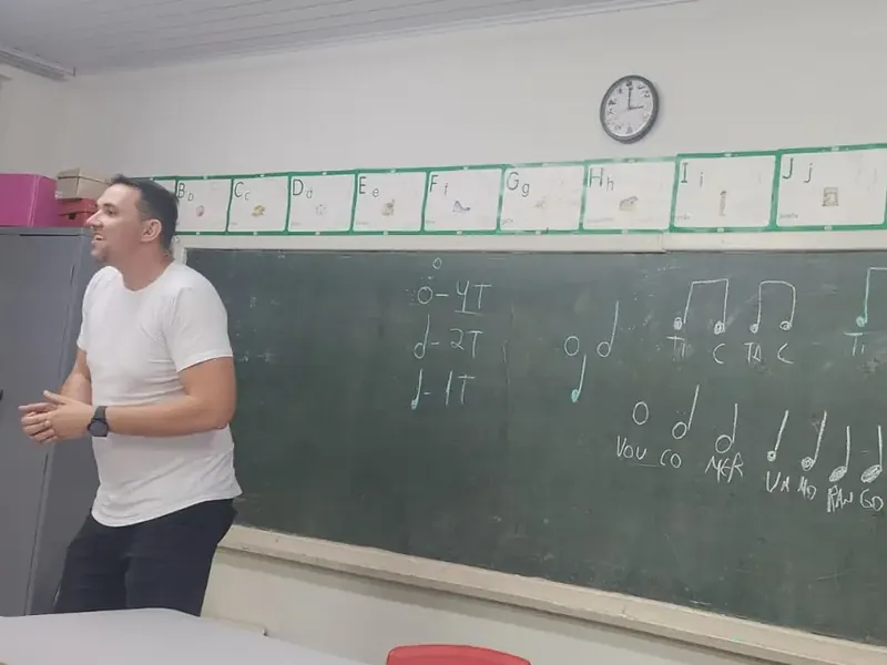 Professor diante da lousa com figuras rítmicas, em aula do projeto de música numa escola de Cajuru